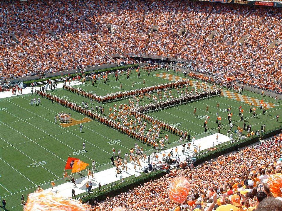 Fans in orange and the marching band on the field at Neyland Stadium in Knoxville