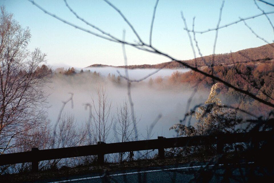 Fog filling a valley seen from the Cherohala Skyway, with a guardrail in the foreground